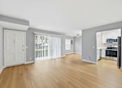 Thumbnail 57 of 133 - A spacious living room with wooden floors and white walls.
