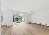 Thumbnail 85 of 133 - A room with wooden floors and white walls, with a view of trees through a glass door.