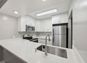 Thumbnail 54 of 133 - A modern kitchen with a white countertop and stainless steel appliances.