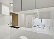 Thumbnail 88 of 133 - A modern kitchen with white cabinets and a stove top oven.