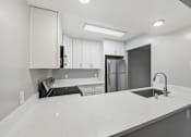 Thumbnail 66 of 133 - A kitchen with white cabinets and a marble countertop.