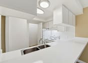 Thumbnail 90 of 133 - A modern kitchen with white countertops and stainless steel appliances.