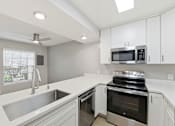 Thumbnail 58 of 133 - A modern kitchen with a stainless steel sink and oven.