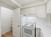 Thumbnail 89 of 133 - A white kitchen with a stove, oven, and refrigerator.