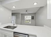 Thumbnail 65 of 133 - A modern kitchen with a white countertop and a stainless steel sink.