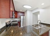 Thumbnail 120 of 133 - A kitchen with a granite countertop and stainless steel appliances.