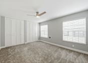 Thumbnail 67 of 133 - A room with a carpeted floor, a ceiling fan, and a window with blinds.