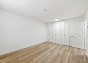 Thumbnail 86 of 133 - A room with white walls and wooden flooring with a row of white closets.