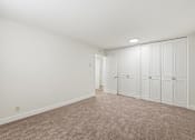 Thumbnail 122 of 133 - A room with white walls and a carpeted floor with a row of closets on one side.