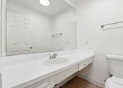 Thumbnail 95 of 133 - A white bathroom with a toilet, sink, and mirror.