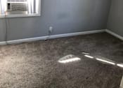 Thumbnail 20 of 31 - A room with a carpeted floor and a window with blinds.