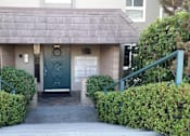 Thumbnail 2 of 8 - A small building with a green door and a sign on it.