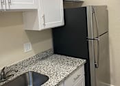 Thumbnail 38 of 43 - A kitchen with a black refrigerator and white cabinets.