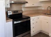 Thumbnail 18 of 36 - a kitchen with a stove and white cabinets
