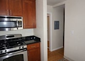Thumbnail 22 of 22 - A kitchen with wooden cabinets and a stainless steel stove top oven.