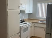 Thumbnail 13 of 37 - A kitchen with white appliances and wooden floors.