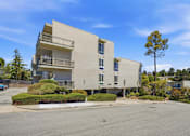 Thumbnail 65 of 92 - A modern apartment building with a parking lot in front.