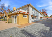 Thumbnail 38 of 67 - A yellow house with a red roof is in front of a white building.