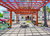 Thumbnail 23 of 25 - A red car is parked under a wooden pergola.
