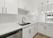Thumbnail 58 of 92 - A kitchen with white cabinets and a black dishwasher.