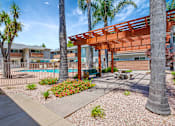 Thumbnail 3 of 25 - A patio area with a pool and a wooden pergola.