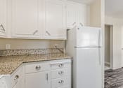 Thumbnail 20 of 51 - A white refrigerator in a kitchen with white cabinets.