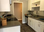 Thumbnail 18 of 43 - A kitchen with white cabinets and a black counter top.