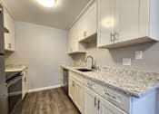 Thumbnail 35 of 50 - A kitchen with white cabinets and a granite countertop.
