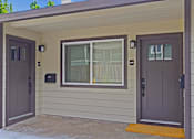 Thumbnail 18 of 27 - A house with a brown door and a window with white curtains.