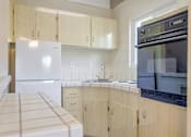 Thumbnail 19 of 32 - A kitchen with a white fridge and wooden cabinets.