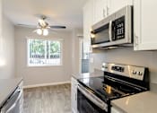 Thumbnail 7 of 27 - A modern kitchen with a black stove top oven and white cabinets.