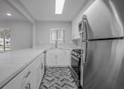 Thumbnail 11 of 31 - A black and white photo of a kitchen with a refrigerator on the right.