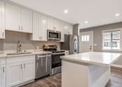 Thumbnail 61 of 62 - A modern kitchen with white cabinets and stainless steel appliances.