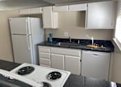 Thumbnail 14 of 43 - A white stove top oven in a kitchen with a black counter top.