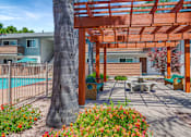 Thumbnail 5 of 25 - A wooden pergola is over a patio with a table and chairs.