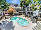 Thumbnail 10 of 43 - A swimming pool in a courtyard surrounded by trees and buildings.