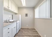 Thumbnail 40 of 42 - A kitchen with white cabinets and a washer and dryer.