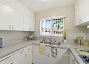 Thumbnail 11 of 33 - A kitchen with white cabinets and a window with a view of a balcony with a yellow towel hanging on the sink.
