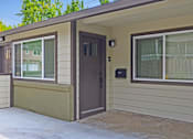 Thumbnail 17 of 27 - A small house with a brown door and a window with white curtains.
