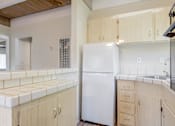 Thumbnail 21 of 32 - A white refrigerator is in a kitchen with wooden cabinets.