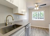 Thumbnail 8 of 27 - A modern kitchen with a stainless steel sink and a ceiling fan.