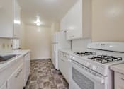 Thumbnail 7 of 29 - A kitchen with white appliances and a tiled floor.