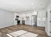 Thumbnail 52 of 67 - A kitchen with white cabinets and a wooden floor.