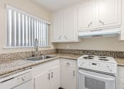 Thumbnail 21 of 51 - A white stove and sink in a kitchen with white cabinets.