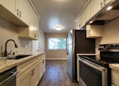 Thumbnail 37 of 50 - A kitchen with a black refrigerator and stove top oven.