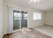 Thumbnail 22 of 37 - A room with a sliding glass door and a ceiling fan.