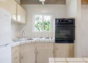 Thumbnail 20 of 32 - A kitchen with a white fridge, black oven and wooden cabinets.