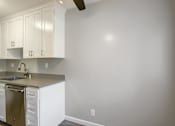 Thumbnail 10 of 27 - A kitchen with white cabinets and a stainless steel sink.