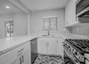 Thumbnail 22 of 31 - A modern kitchen with white cabinets and a black stove top.