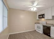 Thumbnail 6 of 13 - an empty kitchen with white appliances and a ceiling fan